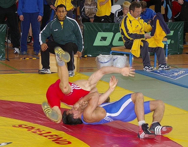 DM_OlbernhauSamstag018.jpg - Eine interessante Technik. Auch dafür bekommt der Kämpfer im blauen Trikot zwei Punkte. Zwar zeigen bei beiden die Schultern Richtung Matte, jedoch ist Blau eindeutig der Ausfürende.Es hat im übrigen jeder Ringer sowohl ein blaues und ein rotes Trikot. Somit wird es für die Kampfrichter leichter, zu unterscheiden, wer die Punkte bekommt.Bei Einzelturnieren entscheidet das Los, wer welche Farbe anzieht, bei Mannschaftskämpfen hat die Heimmanschaft rot, die Gäste treten in blau an.