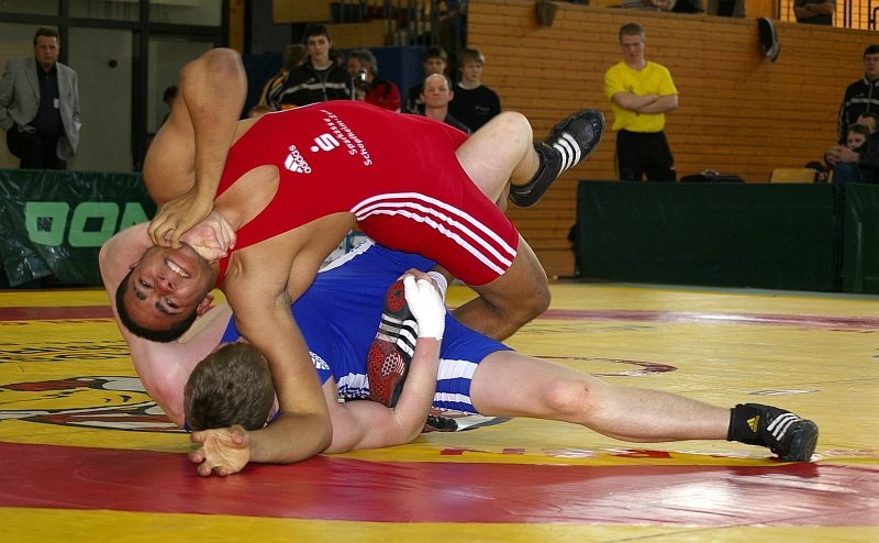 DM_OlbernhauSonntag005.jpg - Hier sieht man eine sehr moderne Technik, die aber grenzwertig ausgefürt wird. Bei der Einsteiger-Rolle klemmt man das Bein des Gegners ein und bringt ihn in ein derartiges Hohlkreuz, dass man sich gut mit ihm zusammen rollen kann, ohne dass die Gefahr besteht, dass er sich befreien kann.Allerdigs ist das Fassen an den Hals verboten. Ebenso wie im übrigen auch jegliche Aktion im Gesichtsbereich und natürlich unfaire Dinge wie schlagen und ähnliches. Auch darf man nicht irgendwelche Gelenke gegen ihre natürliche Bewegungsrichtung bewegen, wie es manchmal bei amerikanischen Wrestling-Shows geschauspielert wird (die mit Ringen aber nichts zu tun haben).